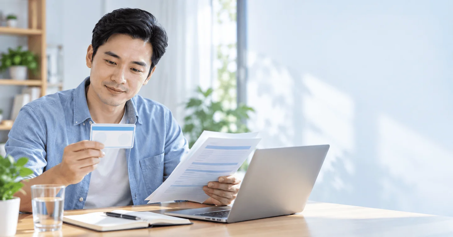 Người đàn ông đối chiếu thẻ bảo hiểm và tài liệu tại nhà