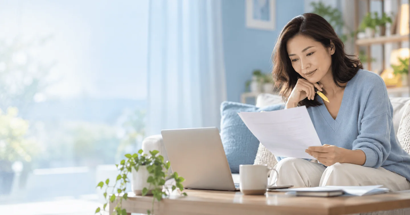 Người phụ nữ đối chiếu các trang tài liệu bên máy tính